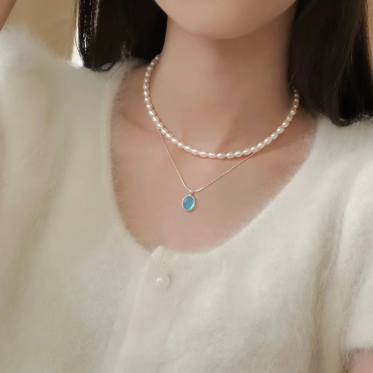Wearing aquamarine and pearl necklaces layered