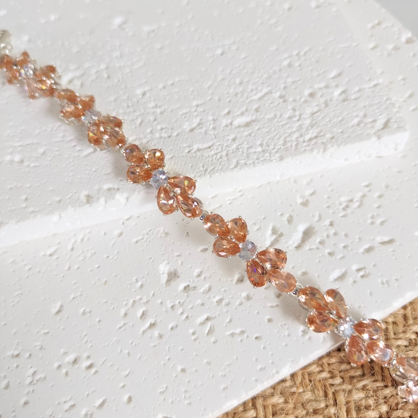 Close-up of amber teardrop zircon and white round gems in bracelet