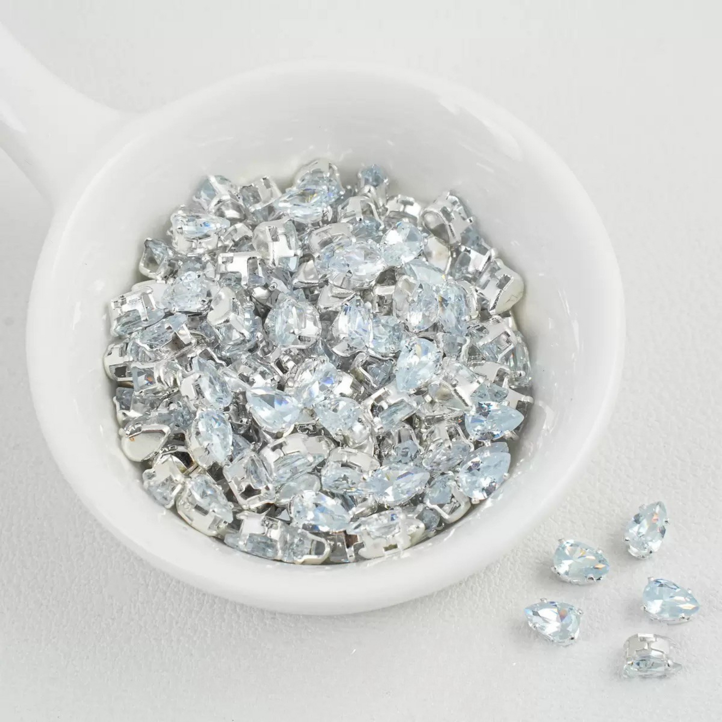White teardrop-shaped zircon spacer bead in silver finish