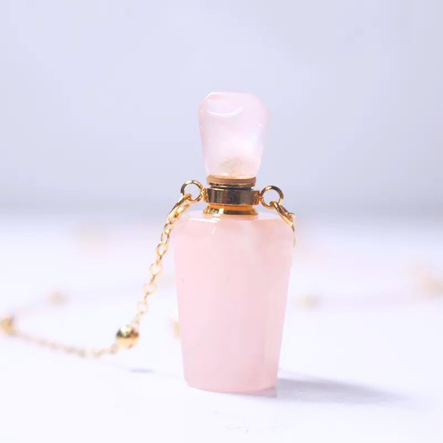 Close-up of rose quartz raw crystal perfume bottle pendant