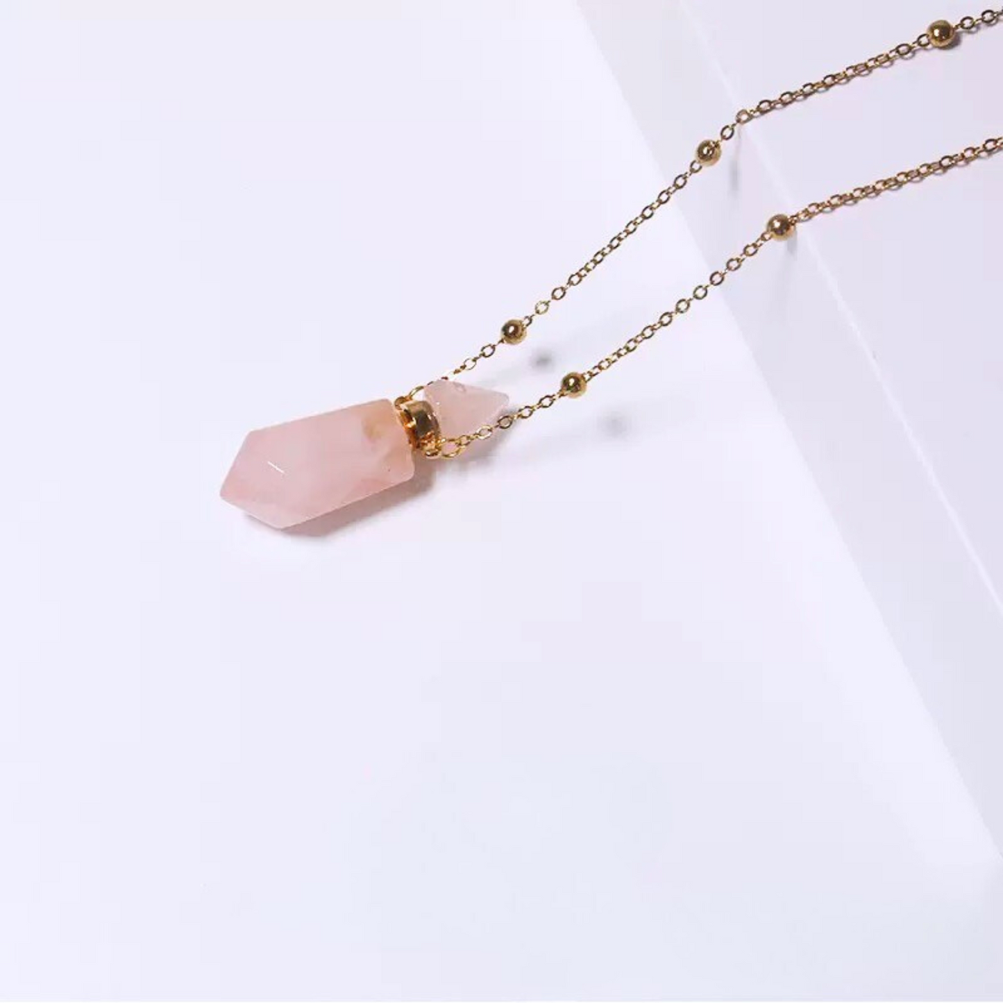 Detailed close-up of rose quartz perfume bottle pendant