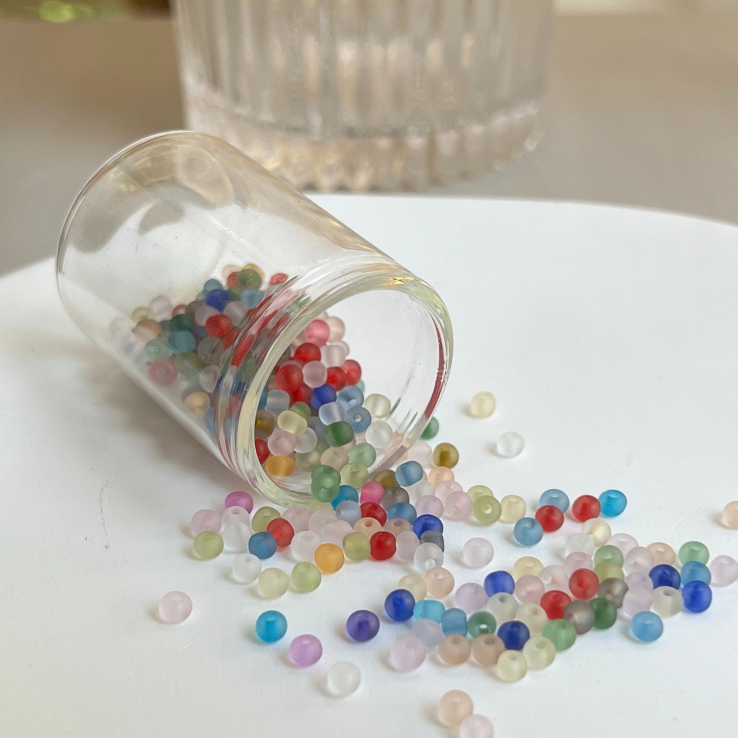 Tiny multicolor seed beads stored in a clear vial, ideal for handmade bracelet making