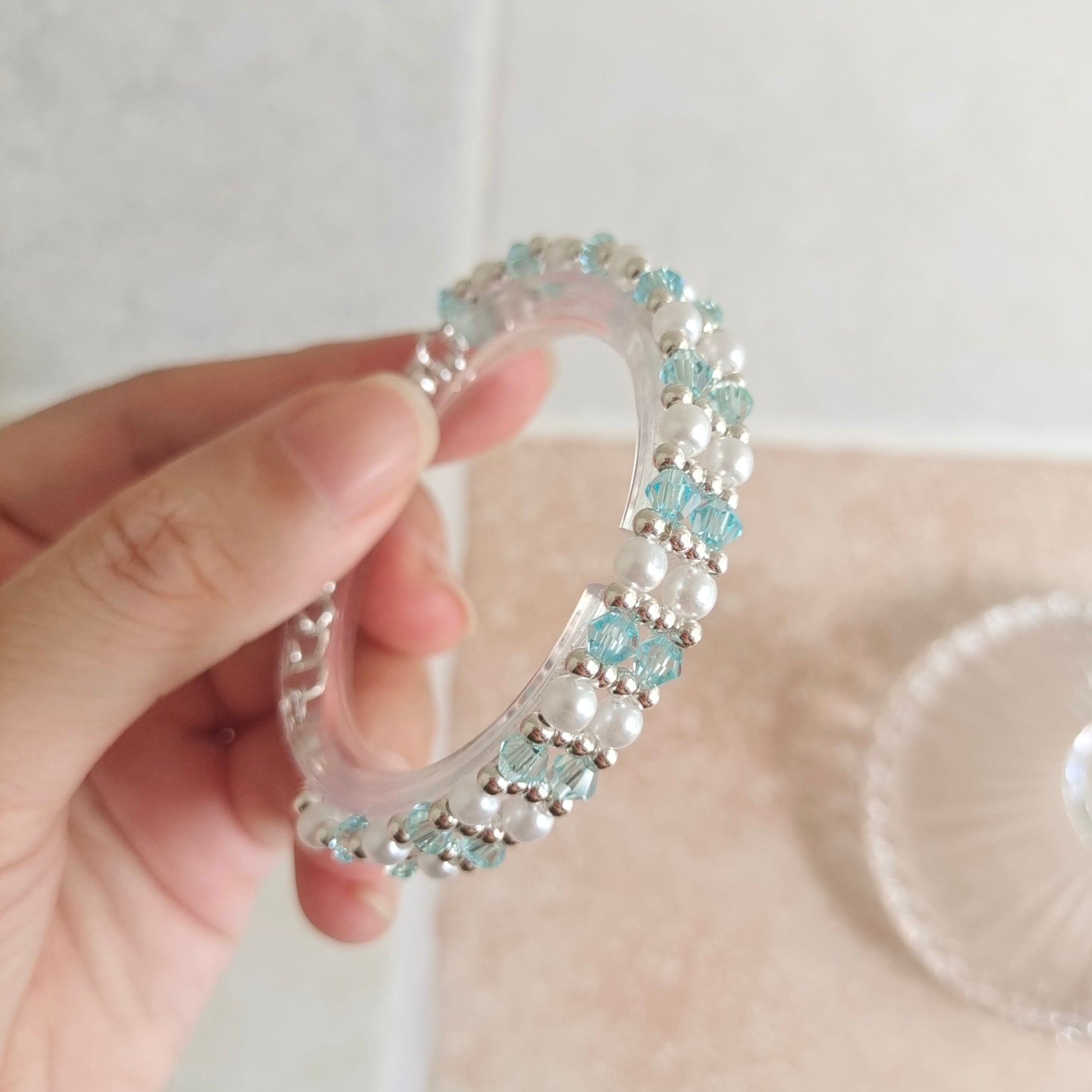 Hand holding a dainty ice blue crystal and pearl bracelet