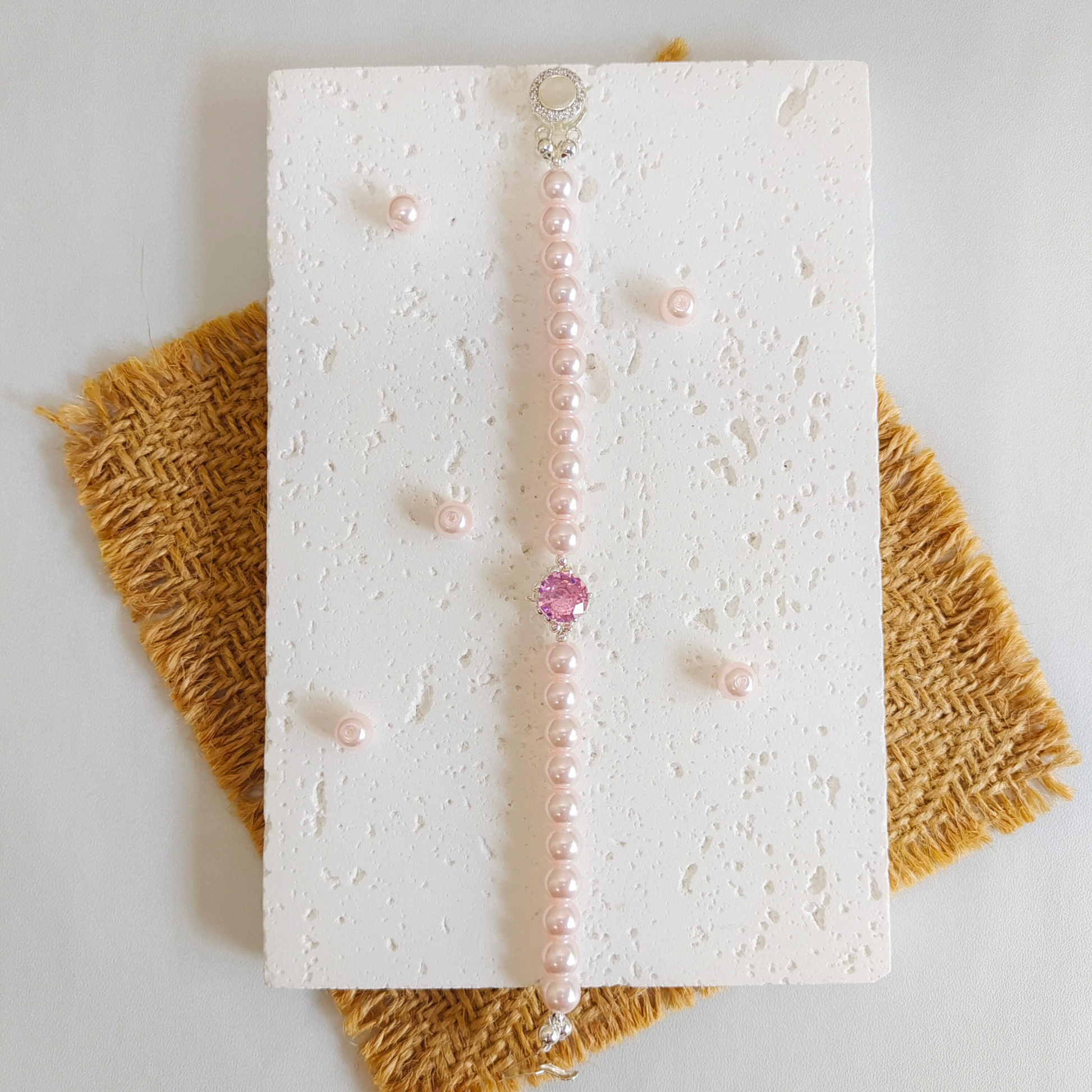 Flat lay of handmade bracelet with pink pearls and pink rhinestones