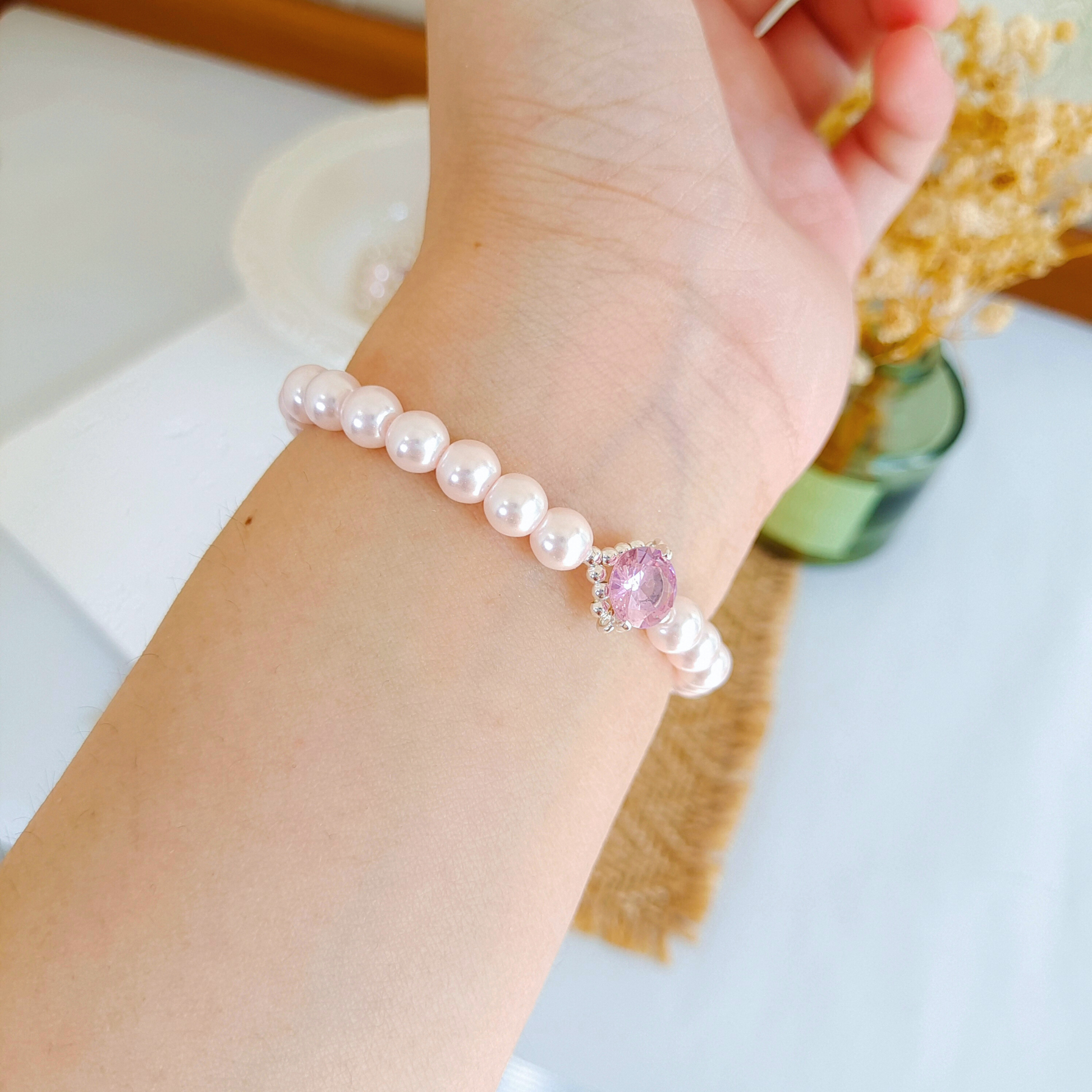 Feminine handmade bracelet with pink gems styled on hand