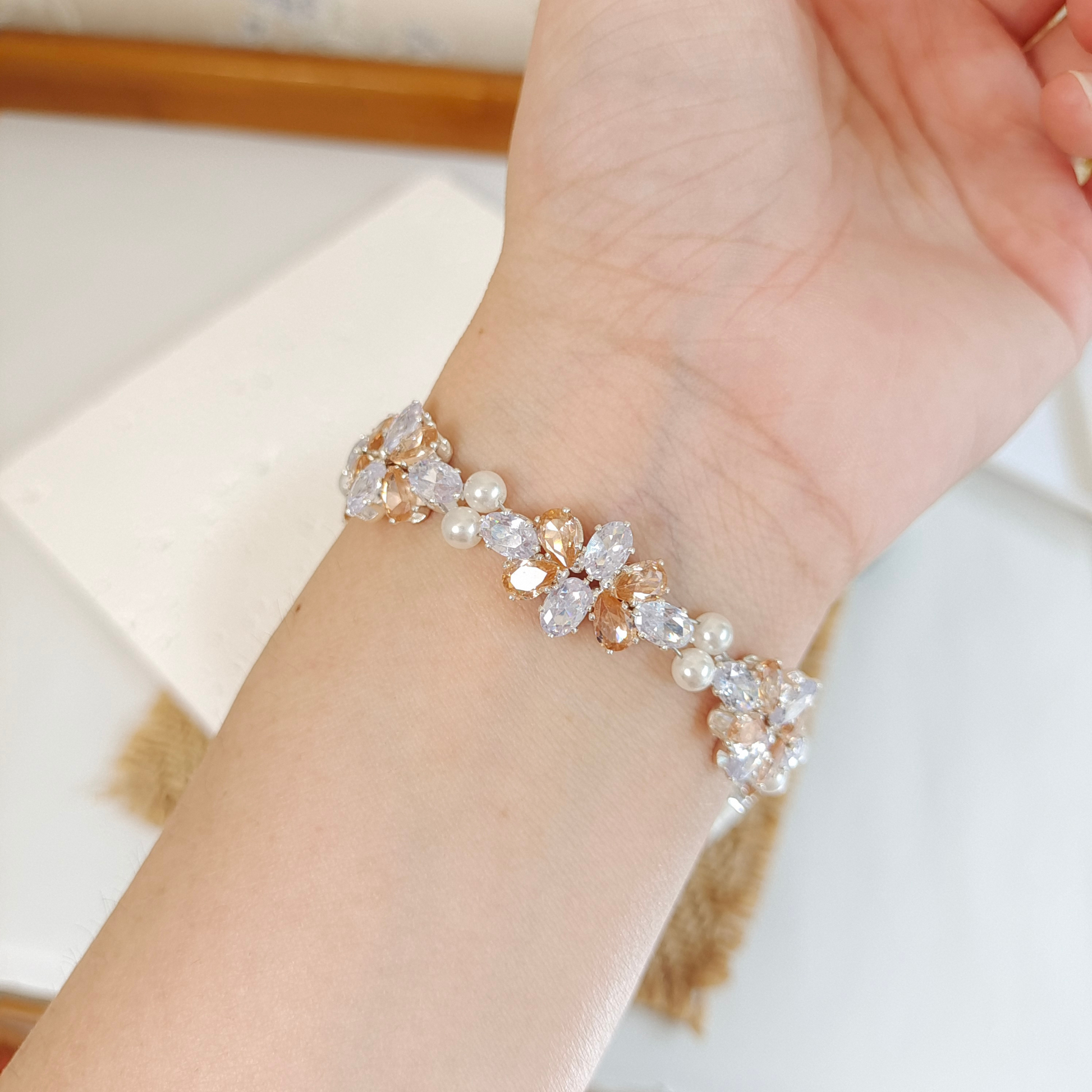 White oval zircon and amber teardrop zircon pearl bracelet worn on wrist
