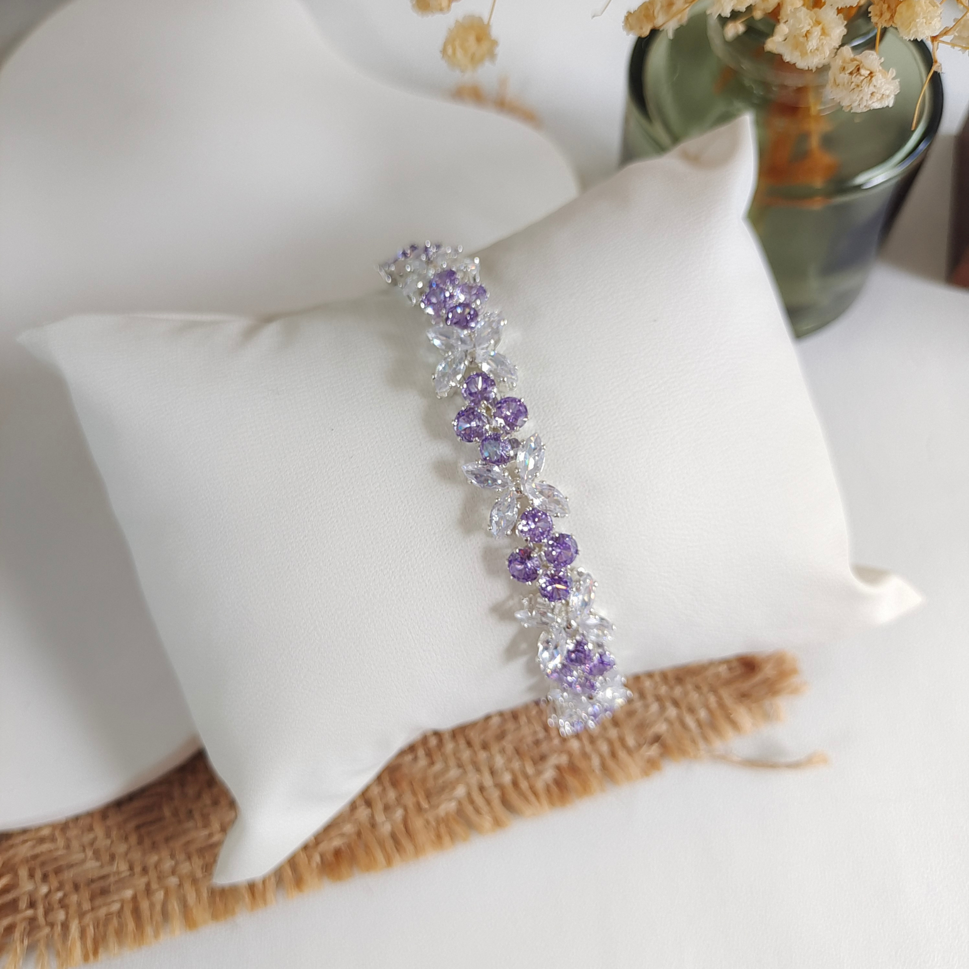 Elegant bracelet with clear marquise and purple round zircon stones on a white cushion