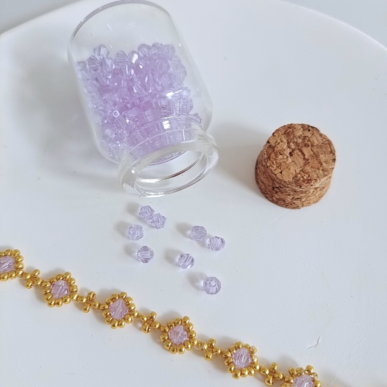 Delicate light purple crystal beads in a mini glass jar