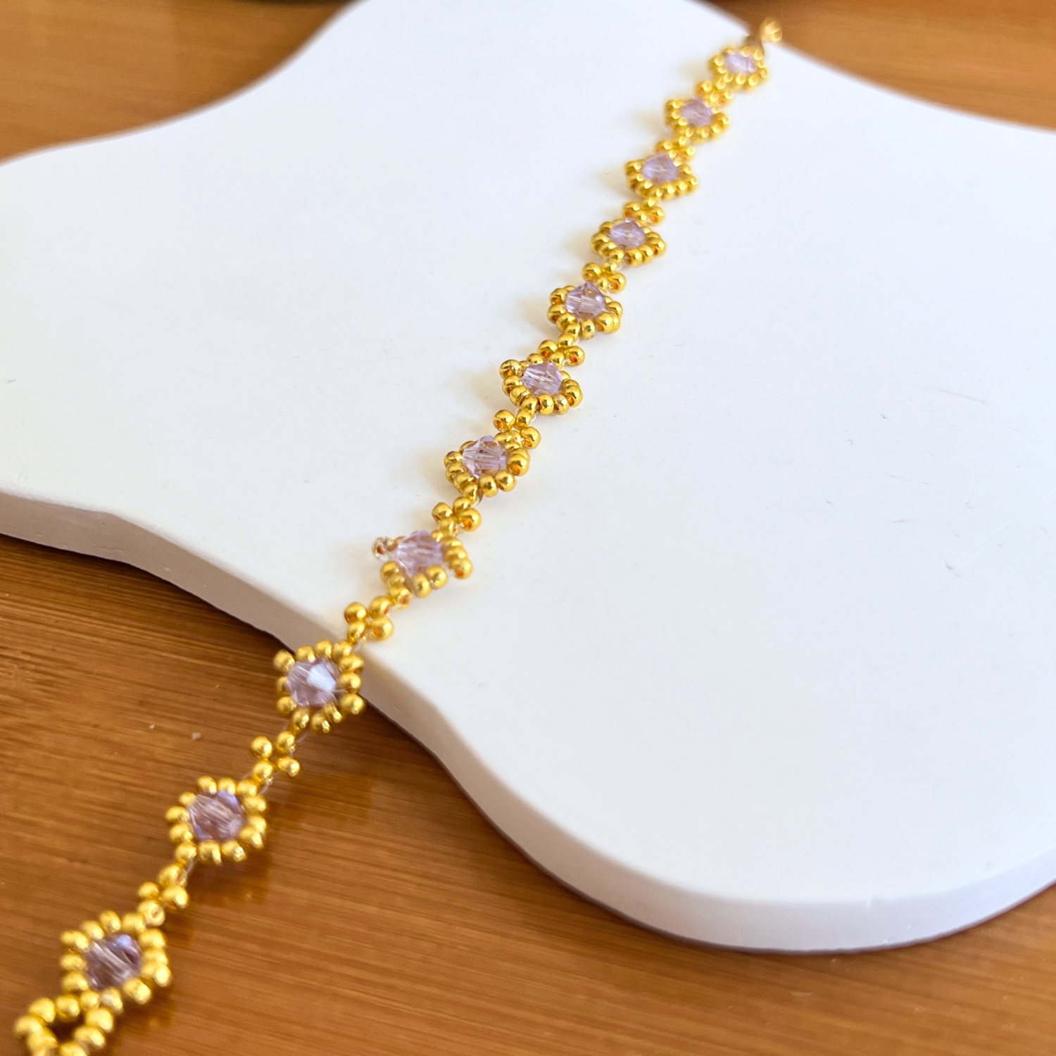 Partial view of a handmade bracelet featuring soft purple diamond beads in a minimalist style